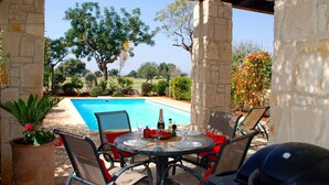An outdoor patio with a pool, stone pillars, and a table set for dining. - Villa HG30 - Destu (Kouklia)