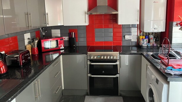 Une cuisine compacte équipée d’appareils électroménagers modernes, notamment un four à micro-ondes, un grille-pain, un four et un lave-linge.