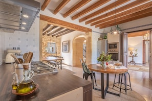 Una cocina con una isla central, un comedor con una mesa redonda y vistas al salón.