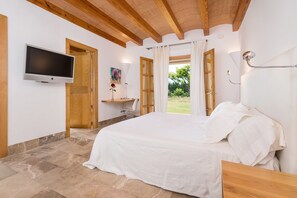 Une chambre à coucher avec un lit, une télévision, un bureau et une fenêtre avec des rideaux.
