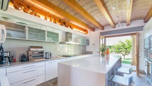 A modern kitchen with a large island, built-in appliances, and a view to the outdoors.