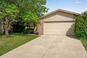 Un garaje residencial con fachada de ladrillo y puerta de color beige.