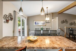 A kitchen with granite countertops, pendant lighting, a dining area with chairs, and a staircase. - 4BD Cheyenne Mountain House with Hot Tub and Grill (Colorado Springs)