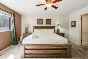 A bedroom with a bed, two bedside lamps, a ceiling fan, and framed pictures on the wall. - 4BD Cheyenne Mountain House with Hot Tub and Grill (Colorado Springs)