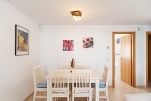A dining area with a white table and chairs, a ceiling light fixture, and wall art.