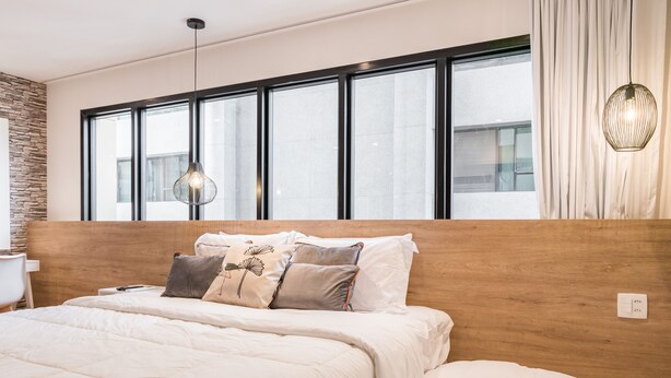 A modern bedroom with a large bed, a wooden headboard, and a large window with curtains. - Cyclinn Faria Lima Itaim (São Paulo)