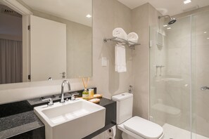 Un baño moderno con lavamanos, inodoro y cabina de ducha de vidrio.