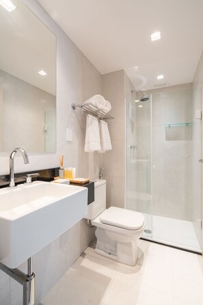 Een moderne badkamer met een grote spiegel, een wastafel, toilet en een douche met glazen wanden.