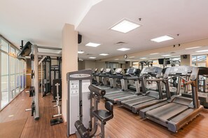 Un gimnasio con cintas de correr, máquinas de pesas y equipamiento de ejercicio.