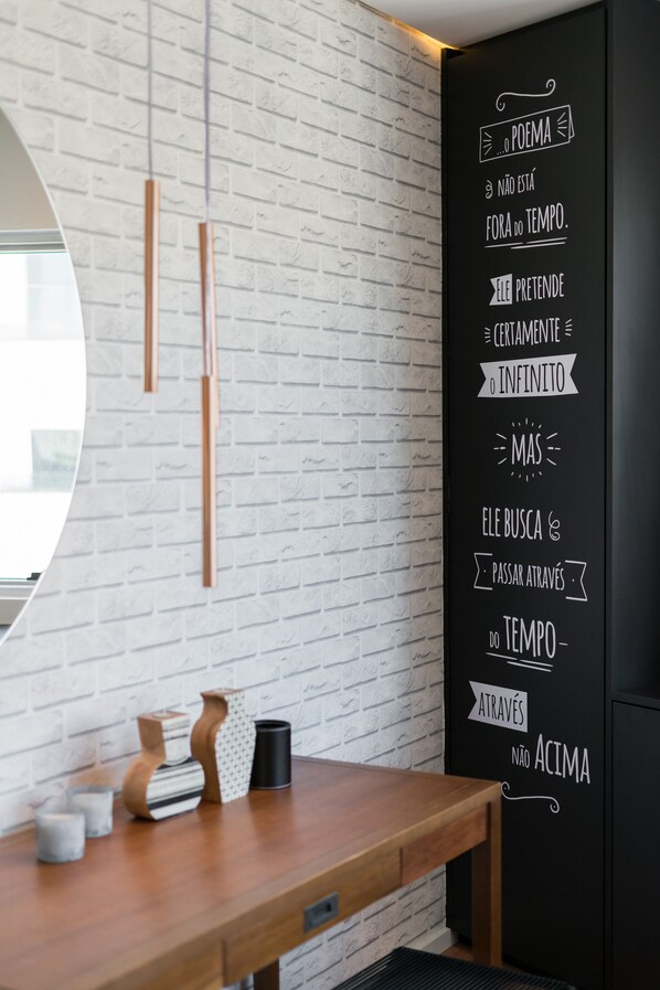 Un intérieur moderne avec un mur en briques blanches, une table en bois agrémentée d’objets décoratifs et un mur noir orné d’un texte inspirant.