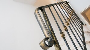 Primer plano de una barandilla de escalera de metal con un pasamanos curvo y detalles decorativos.