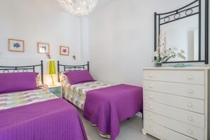 Une chambre avec deux lits, une commode, un miroir et des œuvres d’art accrochées au mur.