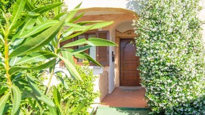 A traditional building with a wooden door, a green pathway, and lush greenery. - Holiday Home 'Sardinia Sea View Pool & Spa' with Pool and Hot Tub (pittulongu)