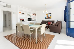 Un salon moderne avec une table à manger, des chaises, un canapé et une porte bleue.