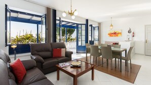 Uma sala de estar moderna com sofá, mesa de centro, mesa de jantar e cadeiras.