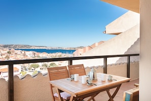 A wooden table with chairs and a view of a coastal town. - Three-Room Apartment in the Center with Sea View (Palau)