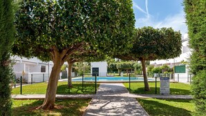 A pathway leading to a swimming pool surrounded by well-maintained trees and a white building. - Family-Friendly Home Casa Noah Close to Beach with Pool, Terrace, Balcony & Wi-Fi (CONIL de la Frontera)