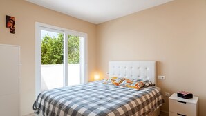 A bedroom with a bed, a nightstand, a wardrobe, and a sliding glass door leading to an outdoor area. - Family-Friendly Home Casa Noah Close to Beach with Pool, Terrace, Balcony & Wi-Fi (CONIL de la Frontera)