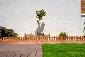 Une terrasse en bois avec un banc, un petit arbre et une clôture en bois.