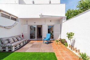 Un patio moderne avec un canapé, une chaise bleue et un petit coin jardin.