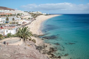 A coastal town with a beach, clear blue waters, and buildings along the shore. - Apartment On the Beach with Pool, Terrace, Balcony, Fantastic Views & Wi-Fi (Morro Jable, Fuerteventura)