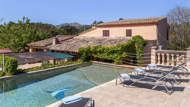 A pool with lounge chairs, a building with a tiled roof, and greenery. - Fantastic Country Estate with Pool, Wi-Fi, Air Conditioning and Tennis Court (Pollensa)