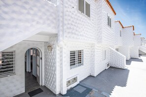 Un edificio blanco con techo de tejas, una puerta y una ventana.