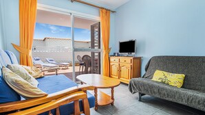 A room with a bed, a sofa, a TV, a table, and a balcony with a view. - Lovely Apartment Close to the Beach with Terrace, Garden & Wi-Fi (Costa Calmar, Fuerteventura)
