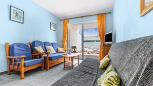 A living room with a sofa, chairs, a table, and a TV. - Lovely Apartment Close to the Beach with Terrace, Garden & Wi-Fi (Costa Calmar, Fuerteventura)