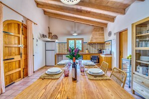 Un espace repas comprenant une table en bois, des chaises et un vase central.