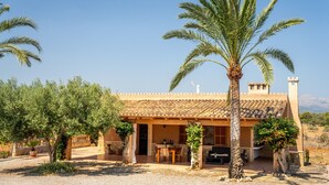 Eine Villa mit Ziegeldach, Sitzgelegenheiten im Freien und Palmen.