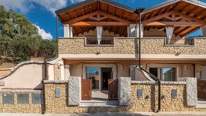 Ein zweistöckiges Steinhaus mit Balkon, Steinmauern und einem Holzdachstuhl.