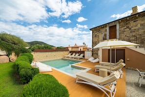 A pool area with lounge chairs and a stone building.