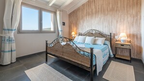 Ein Schlafzimmer mit einem Bett, zwei Nachttischen mit Lampen, einem Fenster mit Vorhängen und einer Holzwand.