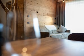En inredning med träpanel, en soffa, ett bord och ett fönster med gardiner.