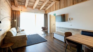 A modern interior with a wooden ceiling, a sofa, a dining table, and a TV mounted on the wall.