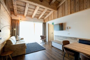Un intérieur moderne avec un plafond en bois, un canapé, une table à manger et un téléviseur fixé au mur.