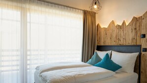 A bedroom with a bed, curtains, and a wooden wall.