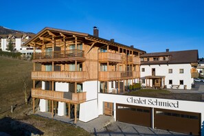 En flervåningsbyggnad i trä med balkonger, ett garage och en skylt med texten ”Chalet Schmied”.
