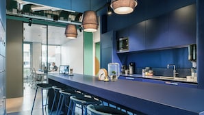 A modern kitchen with a blue countertop, bar stools, and pendant lighting. - The Social Hub Amsterdam West 4 (Amsterdam)