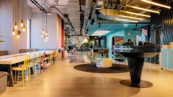 A modern workspace with a long table, colorful chairs, and a unique black sculpture in the center.