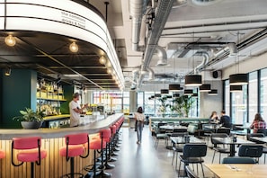 Un espace bar moderne doté d’un comptoir incurvé, de sièges et d’étagères visibles.