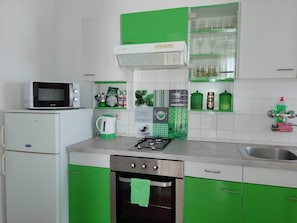 Een keuken met een magnetron, waterkoker, fornuis en een spoelbak.