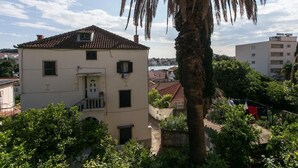 A two-story building with a tiled roof, a balcony, and a view of a body of water. - Apartment Jeanny (Dubrovnik)