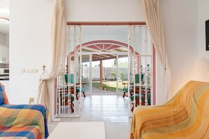 Una habitación con cama, una silla, una mesa y vistas a un patio al aire libre.
