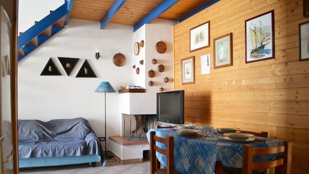 A cozy room with a sofa, a dining table, a TV, and various wall decorations.