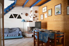 Una habitación acogedora con sofá, mesa de comedor, televisor y varios adornos en las paredes.
