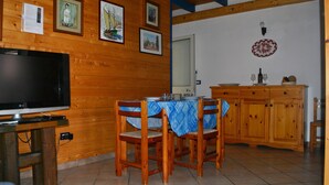 A wooden interior with a TV, dining table, chairs, and cabinets.
