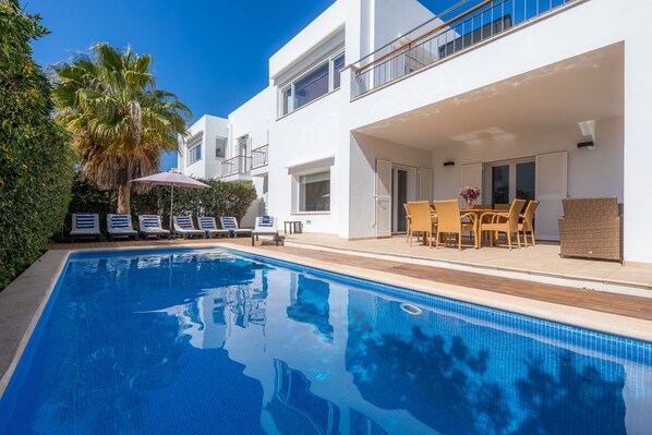 A modern pool area with lounge chairs, a table with chairs, and a palm tree. - Fantastic Villa with Pool, Rooftop Terrace, Air Conditioning, and Wi-Fi (Cala d'Or)