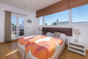 A bedroom with a bed, nightstands, a window with a view, and a sliding door to an outdoor area.